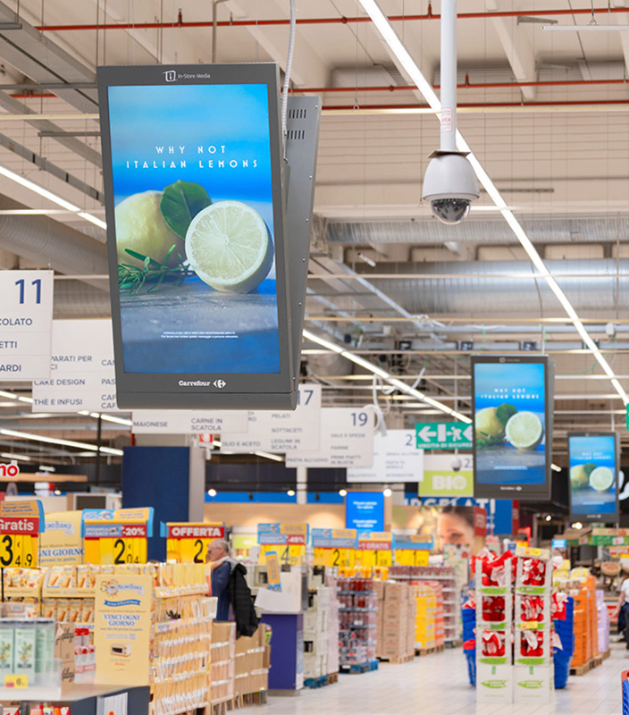 A supermarket aisle with colorful digital signage. The digital screens display an image of lemons with the text 