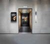 A modern elevator lobby with grey tiled walls and a digital display on the left wall showing 